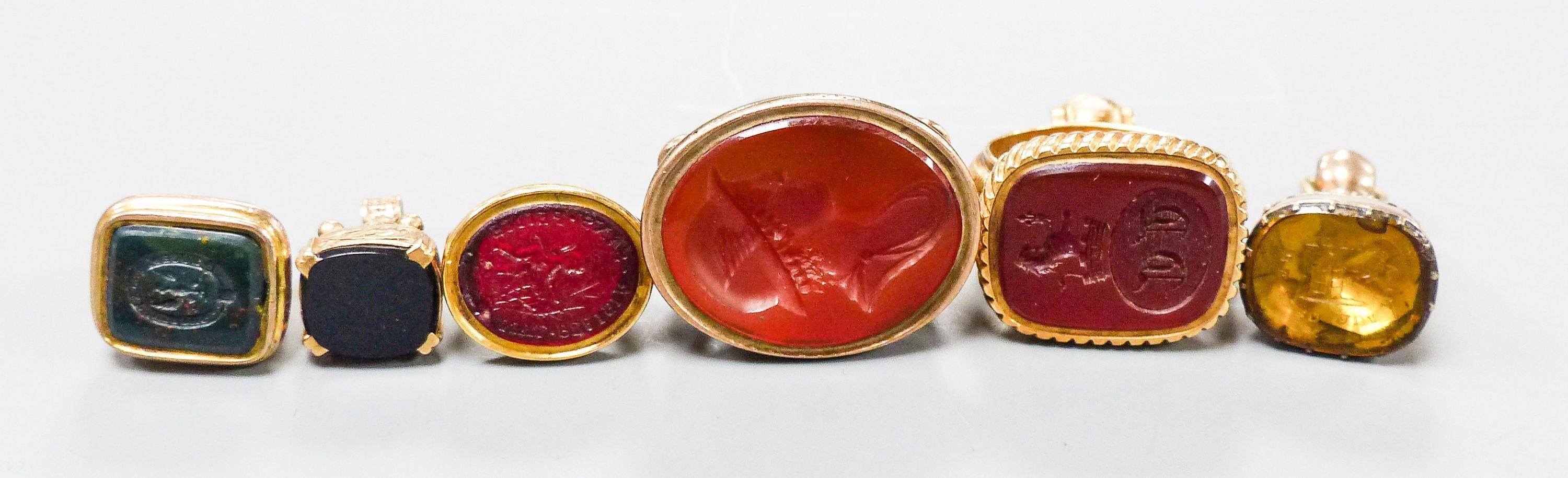 A collection of six 19th century and late assorted yellow metal overlaid and chalcedony set fob seal including one 9ct gold, largest 33mm.